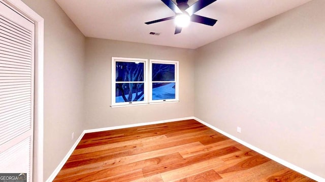 spare room featuring visible vents, wood finished floors, a ceiling fan, and baseboards