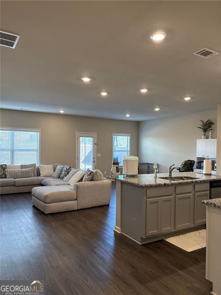 kitchen featuring dark wood-style floors, visible vents, open floor plan, and a sink