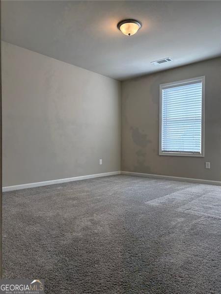 unfurnished room featuring carpet, visible vents, and baseboards