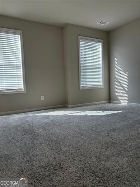 empty room with carpet floors, baseboards, and visible vents