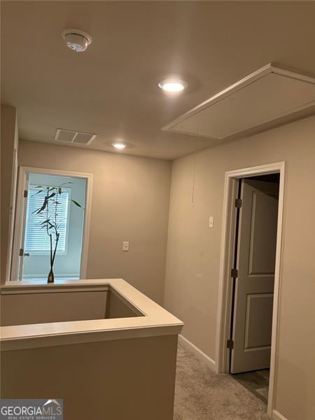 hallway with attic access, visible vents, baseboards, carpet floors, and recessed lighting