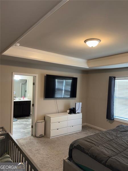 bedroom featuring a tray ceiling, crown molding, and baseboards