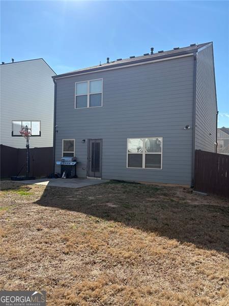 back of house featuring fence and a lawn