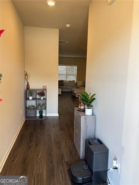 hallway with wood finished floors, visible vents, and baseboards