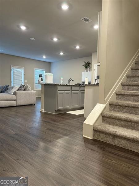 interior space featuring stone countertops, open floor plan, dark wood finished floors, and recessed lighting