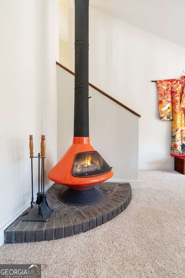 interior details featuring a wood stove, carpet flooring, and baseboards