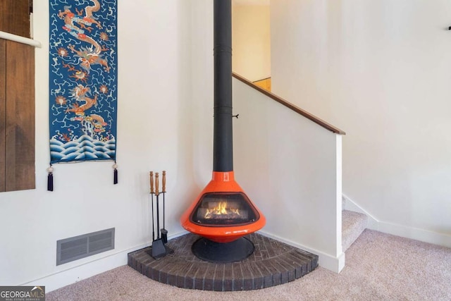 interior details featuring carpet, a wood stove, visible vents, and baseboards