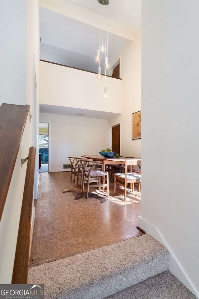 dining space featuring baseboards and a high ceiling