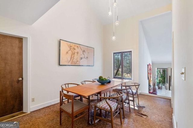 dining room featuring baseboards and high vaulted ceiling