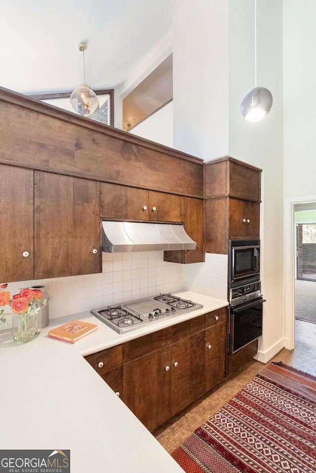 kitchen with light countertops, decorative light fixtures, under cabinet range hood, and black appliances