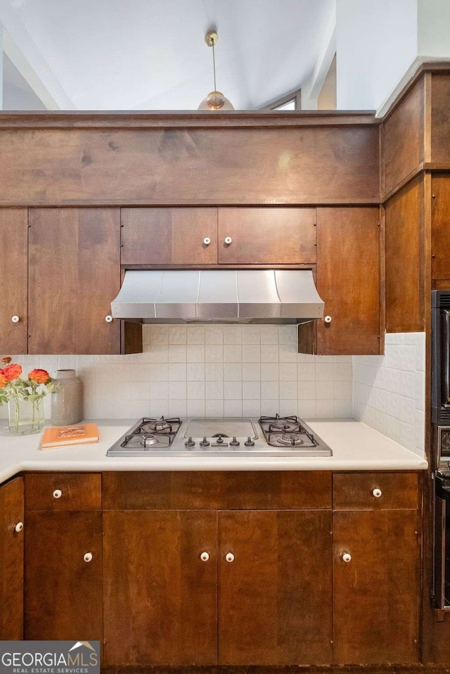 kitchen with light countertops, backsplash, gas stovetop, and exhaust hood