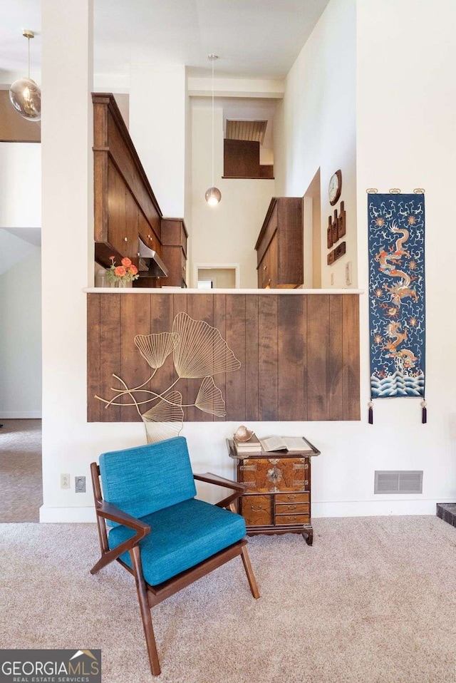 sitting room featuring carpet floors, a towering ceiling, visible vents, and baseboards