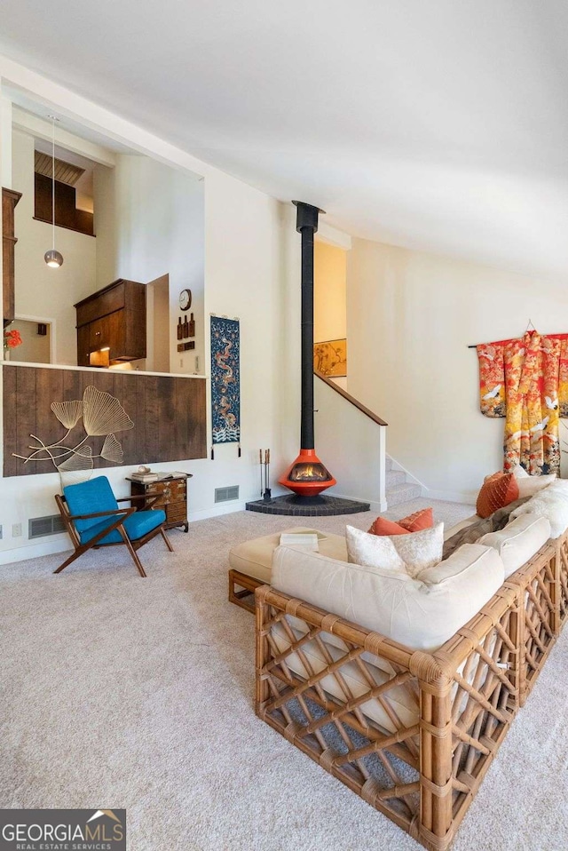 living area with a wood stove, carpet flooring, and visible vents