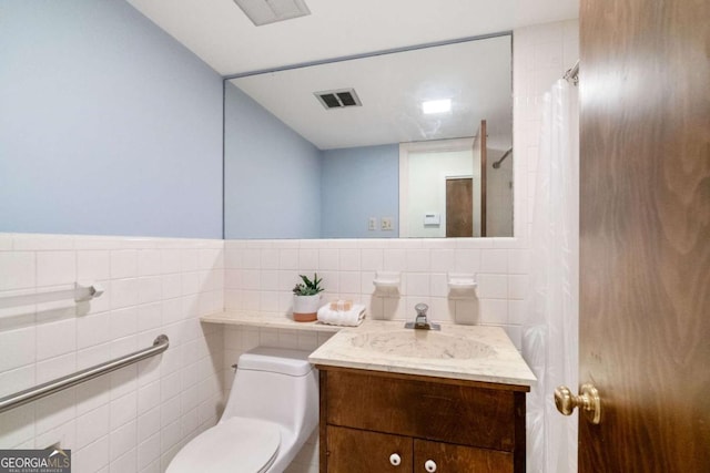 bathroom featuring toilet, visible vents, vanity, and tile walls