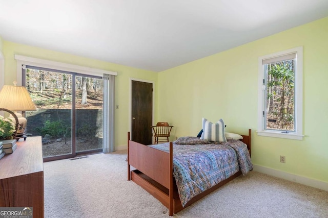 bedroom featuring access to exterior, light colored carpet, and multiple windows