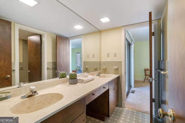 bathroom featuring double vanity, visible vents, tile walls, and a sink