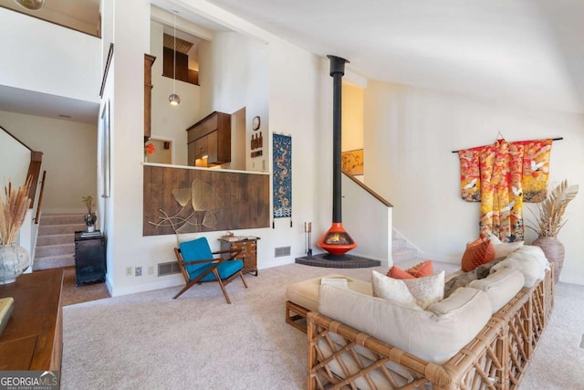 carpeted living room featuring visible vents, stairway, and a towering ceiling