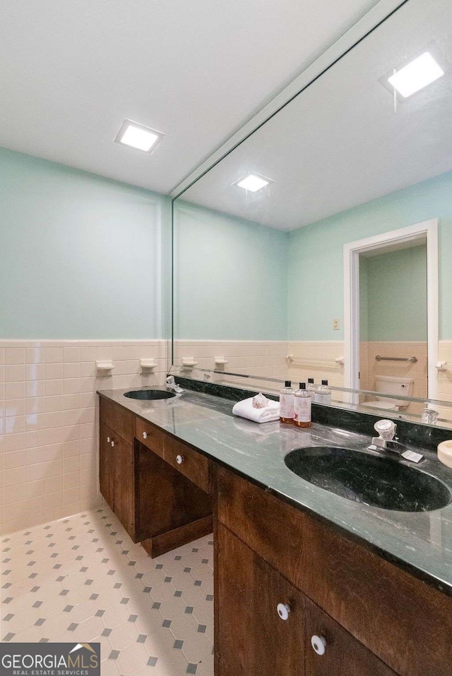 full bathroom featuring a wainscoted wall, tile walls, and vanity