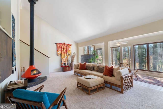 carpeted living area featuring a ceiling fan, a wood stove, and high vaulted ceiling