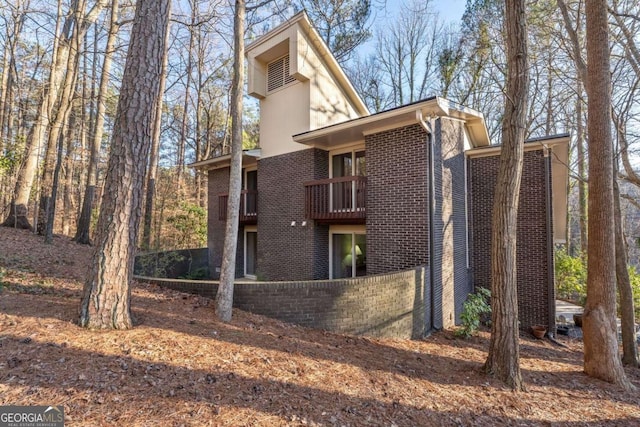 back of house featuring brick siding and a balcony