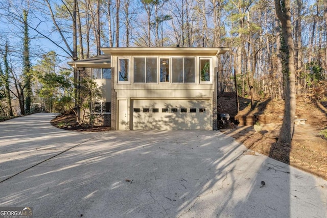 view of side of home with an attached garage, driveway, and brick siding