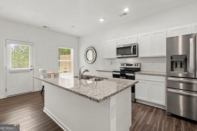 kitchen featuring stainless steel appliances, white cabinetry, a sink, and a center island with sink