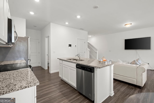 kitchen featuring stainless steel appliances, open floor plan, white cabinetry, and a center island with sink