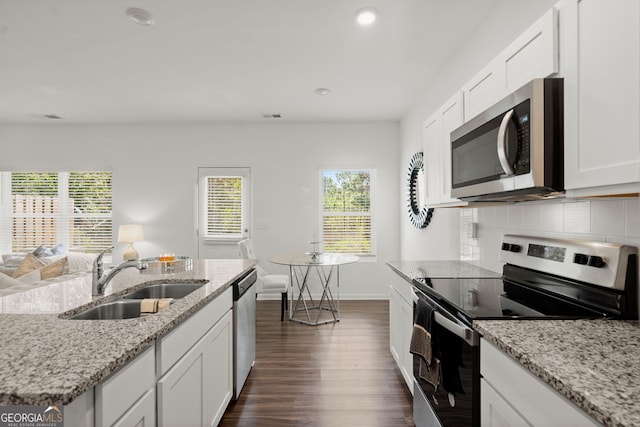 kitchen with light stone counters, decorative backsplash, appliances with stainless steel finishes, white cabinets, and a sink