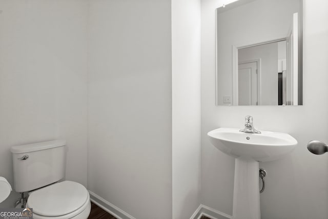 half bathroom with a sink, toilet, and baseboards