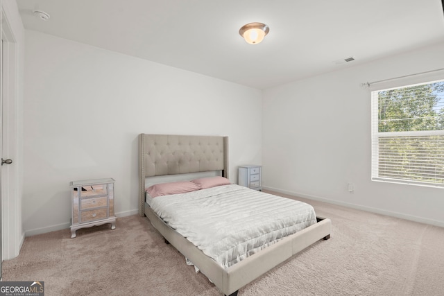 bedroom with baseboards, visible vents, and light colored carpet