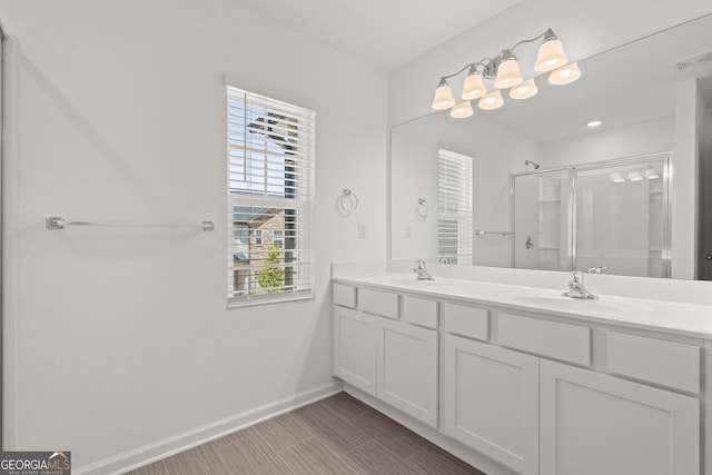 bathroom featuring double vanity, visible vents, a sink, a shower stall, and baseboards