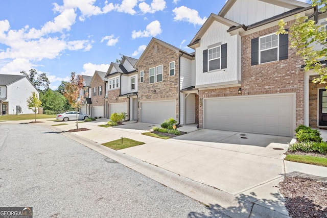 townhome / multi-family property featuring a garage, concrete driveway, a residential view, board and batten siding, and brick siding