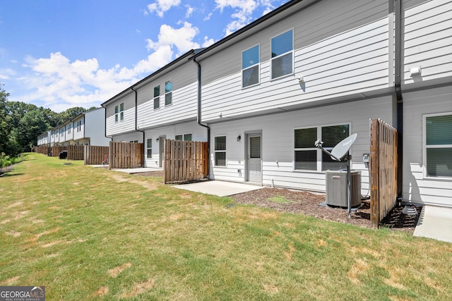 rear view of house with a lawn, fence, a patio, and central air condition unit