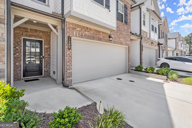 view of exterior entry with driveway, a garage, a residential view, and brick siding