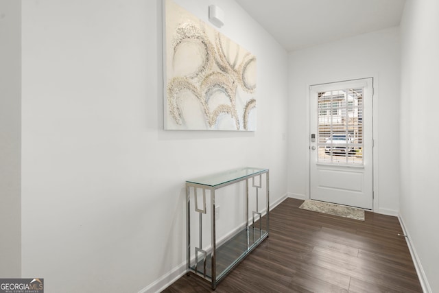 doorway with dark wood finished floors and baseboards