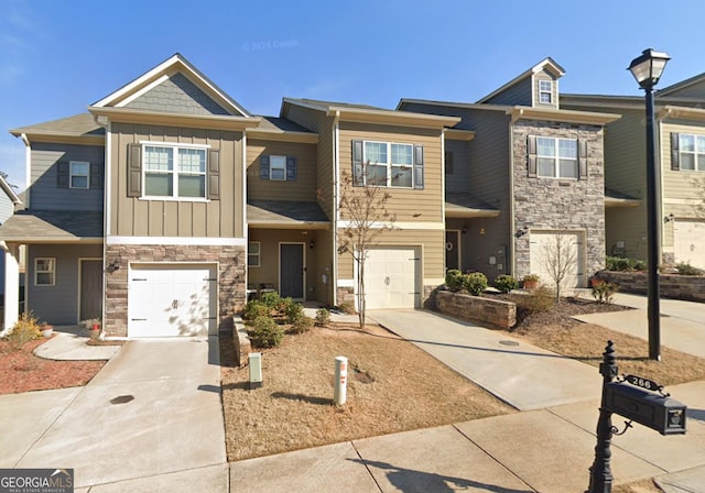 townhome / multi-family property featuring driveway, stone siding, a garage, and board and batten siding