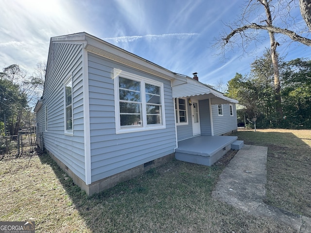 view of front of house with crawl space, fence, and a front lawn