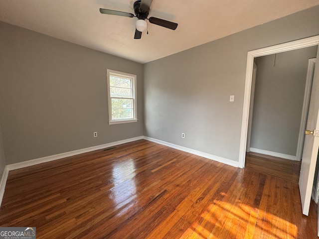 interior space featuring a ceiling fan, dark wood finished floors, and baseboards