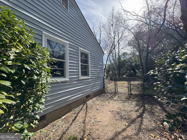 view of home's exterior with crawl space, fence, and a gate