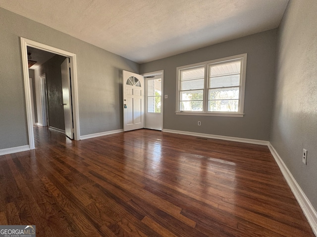 entryway featuring dark wood-style flooring, a textured ceiling, and baseboards