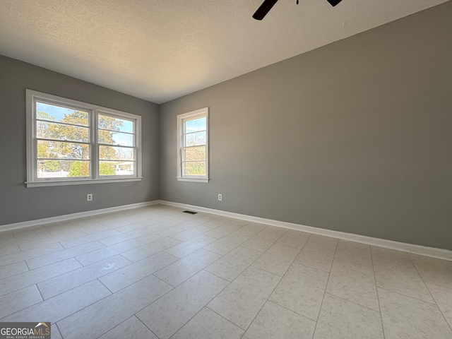 empty room featuring ceiling fan, visible vents, baseboards, and a textured ceiling