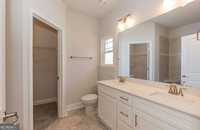 bathroom featuring double vanity, a sink, visible vents, and a walk in closet