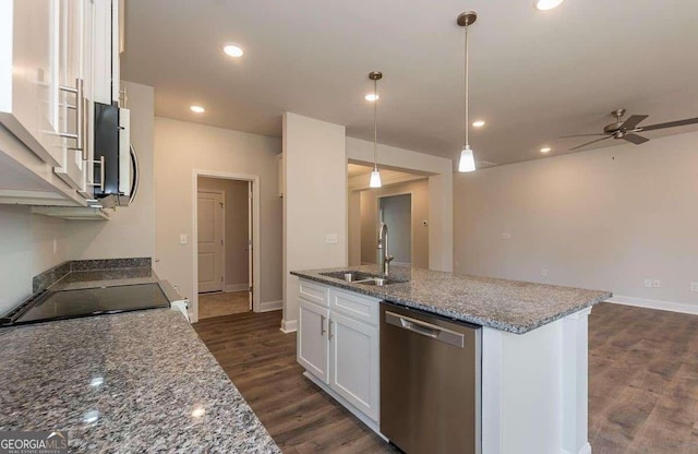 kitchen featuring stone countertops, a sink, white cabinets, hanging light fixtures, and appliances with stainless steel finishes