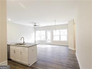 kitchen with white cabinets, an island with sink, open floor plan, hanging light fixtures, and a sink