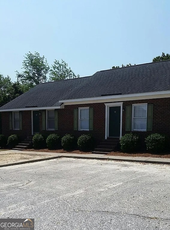 ranch-style house featuring entry steps, brick siding, and roof with shingles