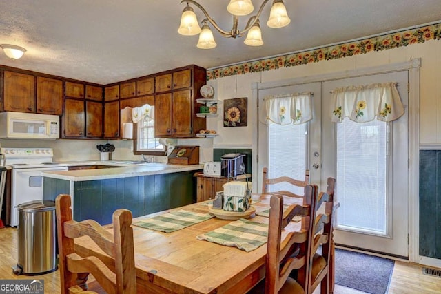 dining area with a chandelier, french doors, a textured ceiling, and light wood-type flooring