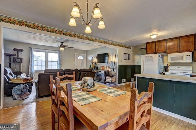 dining area with light wood-style flooring and ceiling fan with notable chandelier