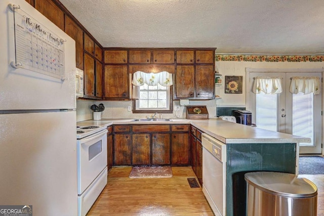 kitchen featuring white appliances, light wood finished floors, light countertops, a textured ceiling, and a sink