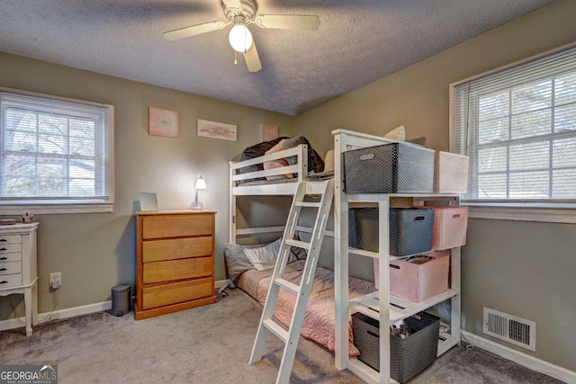 carpeted bedroom featuring a textured ceiling, multiple windows, visible vents, and baseboards