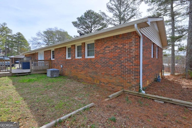 view of side of property with fence, a deck, cooling unit, and brick siding